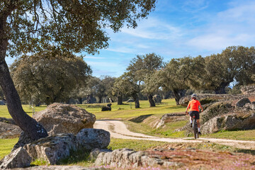 nice senior woman cyling with her electric mountain bike in a stone oak forest of the Extremadura department of Spain