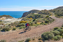 Nice Senior Woman Cycling With Her Electric Mountain Bike In The Volcanic Nature Park Of Cabo De Gata, Costa Del Sol, Andalusia, Spain
