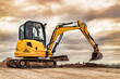 Mini excavator at the construction site on the edge of a pit against a cloudy blue sky. Compact construction equipment for earthworks. An indispensable assistant for earthworks.