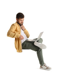 Thoughtful young bearded man with laptop sitting in chair on white background