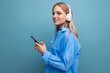 © Ivan Traimak - attractive girl in wireless large headphones with a phone in her hands listens with pleasure to music from the playlist on a blue background