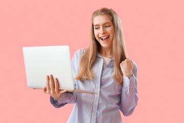 Happy female programmer with laptop on pink background