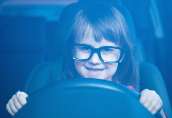 Driving shool. Happy cute little child girl learns to drive. Humorous photo.