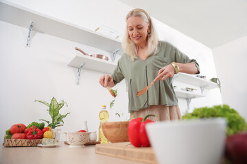 Canvas Print - Mature woman making vegetable salad at table in kitchen