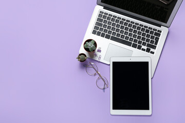 Composition with laptop, tablet and eyeglasses on lilac background