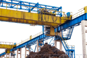 A special yellow-blue hoist crane for moving goods, in particular scrap metal.