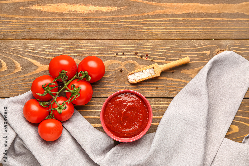 Bowl with tasty tomato paste and fresh vegetables on wooden background