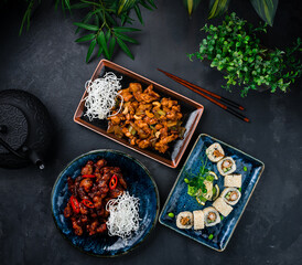 Wall Mural - Asian cuisine set of chicken with onion, celery, cashew nuts, pork in Thai sweet chili sauce and sushi roll set with shrimps tempura, cucumber, onion.