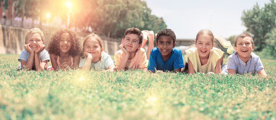happy team of friends children resting on grass at sunny day in park