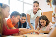 © JackF - Young female teacher and happy schoolkids playing interesting learning board game during lesson in classroom