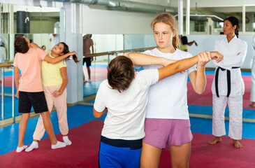 Wall Mural - Teenage boys and girls in pairs practicing self-protection during group class at gym