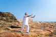 © CandyRetriever  - Asian senior man practicing meditation with nature on rocky coastal hill. Retirement elderly people do outdoor relaxing tai chi yoga exercise at summer sunset. Mental health care motivation concept.