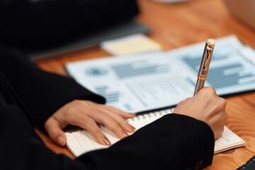 Closeup on BI dashboard on meeting desk with businesspeople analyzing or planning business strategy with hands pointing on financial paper reports as concept of harmony in office workplace.