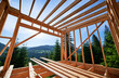 Wooden frame building under construction close to forest. Beginning of new construction of cozy house or a cottage on the edge of forested mountain area. Concept of contemporary architectural design.