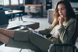 © undrey - Woman reading document sitting in office with her legs on desk