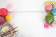 multicolored woolen balls with granny sqaure and crochet hook on white wooden ground with space for text