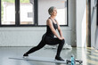 © LIGHTFIELD STUDIOS - full length of cheerful senior woman in sportswear doing lunges on fitness mat.