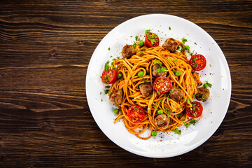 Wall Mural - Spaghetti with meatballs in tomato sauce on wooden table
