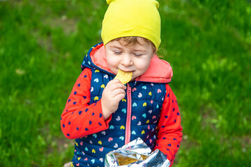 Poster - The child eats chips in the park. Selective focus.