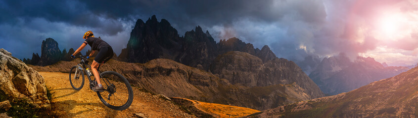 Woman ride electric mountain bikes in the Dolomites in Italy. Mountain biking adventure on beautiful mountain trails.