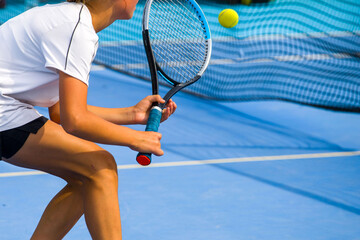 Tennis player playing tennis on a hard court on a bright sunny day	