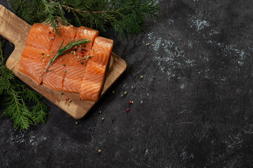 Salmon. Fresh raw salmon fish fillet with cooking ingredients, herbs and lemon on black background