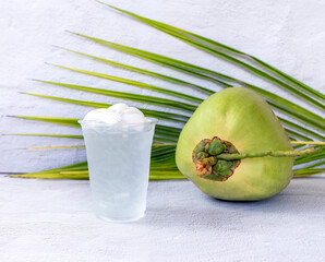 Ice coconut water drink in a plastic glass and coconut on white background