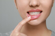 © New Africa - Woman showing healthy gums on grey background, closeup