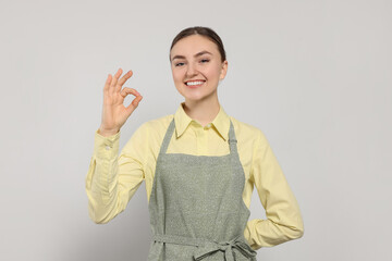 Wall Mural - Beautiful young woman in clean apron with pattern on light grey background