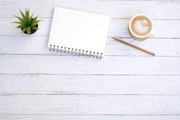 Wall Mural - Blank notepad and coffee cup with green plant on modern white table desk background ,Top view with copy space
