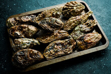 Closed Oysters, Fresh Oyster Shell, Mollusks In Seafood Market. On A Black Stone Background. Side View