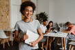 © Drobot Dean - African woman holding laptop while standing in office with her colleagues on a background