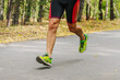 © Real Sports Photos - legs male runner running on road in city park race, autumn marathon, fallen yellow leaves on ground