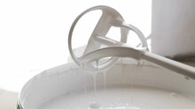 Draining White Paint From Mixer Stick In Bucket, Closeup