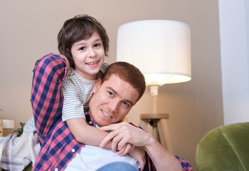 Father and son share a heartwarming embrace on a comfortable sofa, their eyes filled with love and happiness. A moment of pure connection and joy essence of the bond between a father and his child.