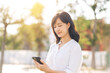 © Jirawatfoto - Portrait beautiful young asian woman with smart mobile phone around outdoor nature view in a sunny summer day