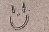 Fototapeta  - Cara sonriente dibujada sobre la arena de la playa