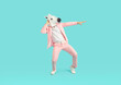 © Studio Romantic - Full length photo of funny man wearing bright pink suit in animal head horse mask dancing on studio blue background. Guy having fun. Entertainment, party, humor and advertisement concept.