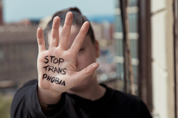 girl With the palm of her hand painted with the message stop transphobia