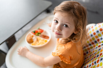 Wall Mural - Little girl have a balanced breakfast in home kitchen in the morning