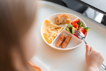 Wall Mural - Little girl have a balanced breakfast in home kitchen in the morning