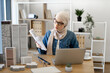 © sofiko14 - Thoughtful muslim lady in hijab directing building model at laptop camera while working on urban design project in modern workspace. Experienced engineer holding online briefing via video call app.