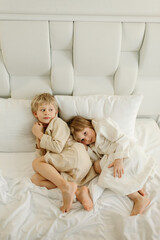 Wall Mural - Brother and sister lying on the bed in bathrobes after a shower