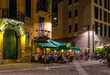 Old street with restaurant tables Milan, Italy. Night cityscape of Milan. Architecture and landmarks of Milan.