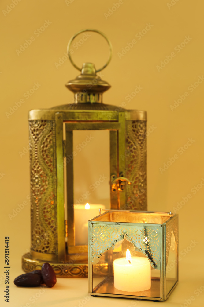 Muslim lamps with burning candles and dates on color background