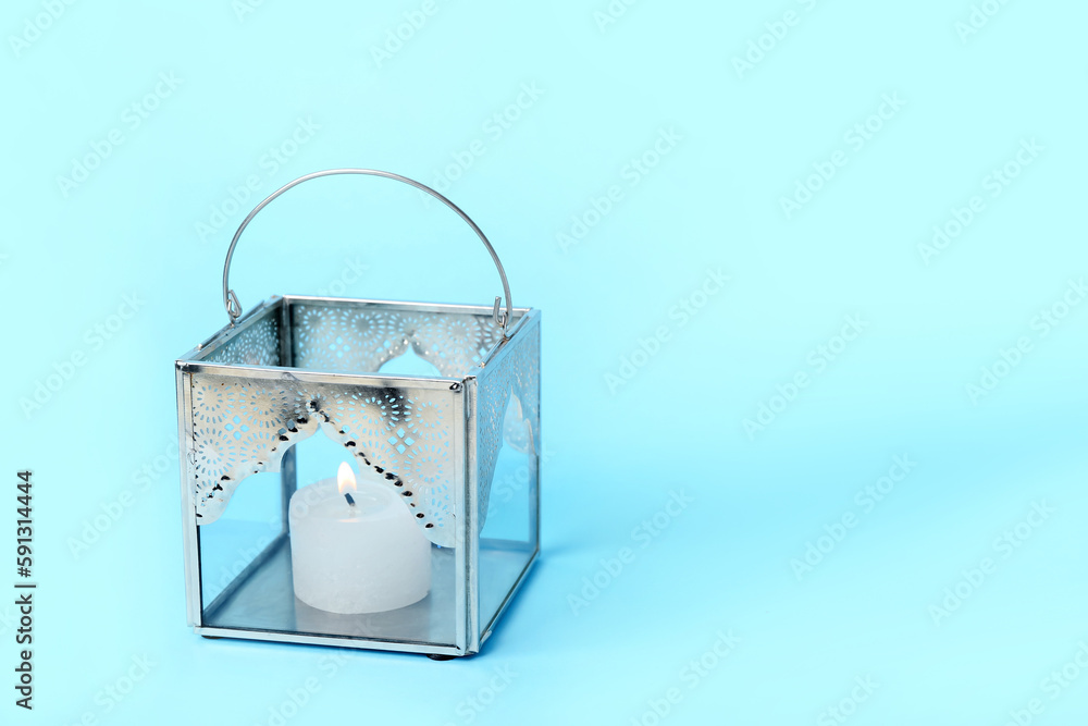 Muslim lamp with burning candle on blue background