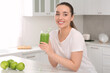 © New Africa - Beautiful young woman holding mason jar with delicious smoothie in kitchen