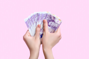 Woman with hryvnia banknotes on pink background