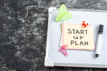Wall Mural - top view start up plan note on sticker inside open copybook on a gray background school lesson stude