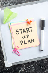 Wall Mural - top view start up plan note on sticker inside open copybook on gray background school lesson student